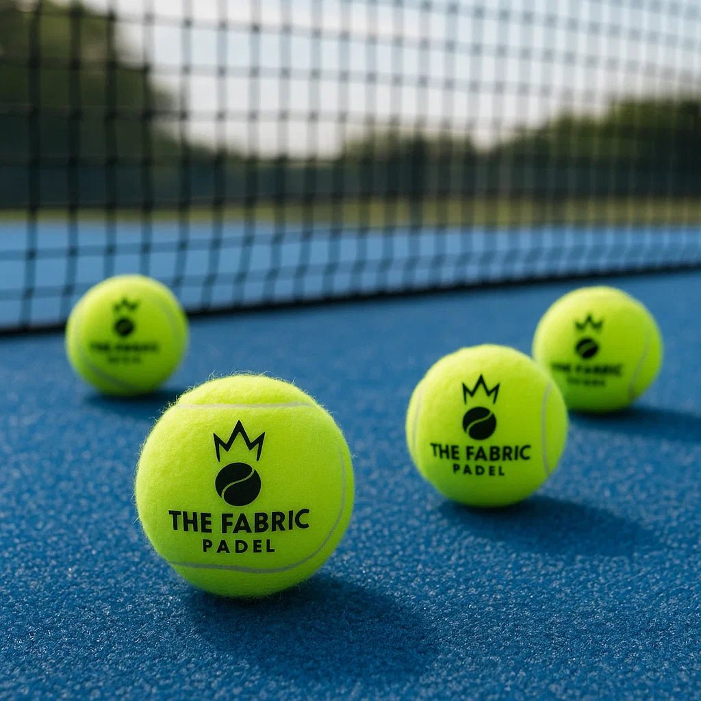 4 bolas con logo  the fabric padel en la moqueta con red de fondo