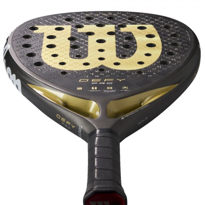 PALA WILSON DEFY PRO V1 2025 en vista inclinada desde el frontal, con acabado dorado, textura rugosa y marco de carbono